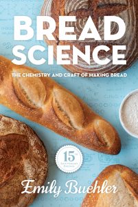 cover of 15th anniversary edition of the book Bread Science, with an aerial view of loaves of bread and chemical equations written on the surface behind them